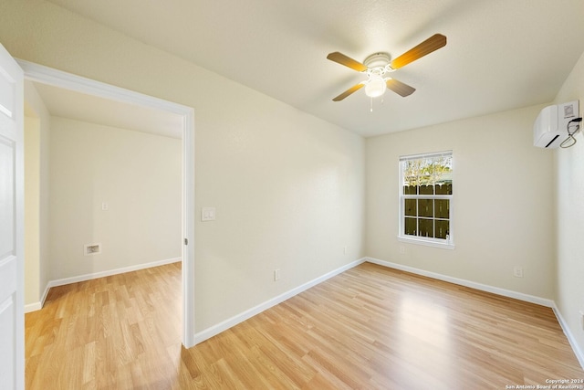 spare room featuring ceiling fan, a wall mounted AC, and light hardwood / wood-style flooring