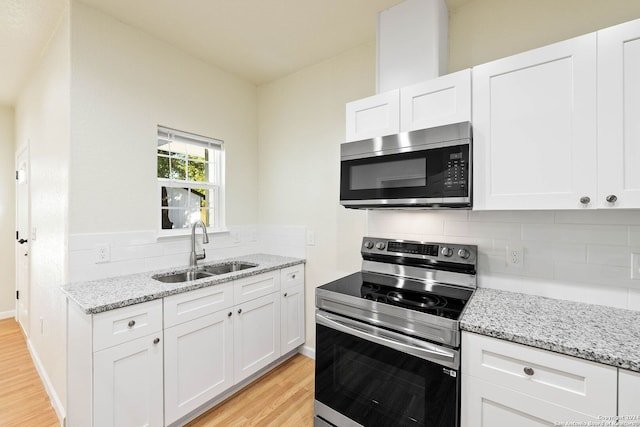 kitchen featuring white cabinets, sink, light hardwood / wood-style flooring, decorative backsplash, and appliances with stainless steel finishes