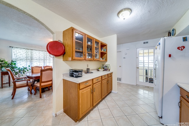 kitchen featuring white refrigerator, light tile patterned floors, and a textured ceiling