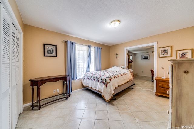 tiled bedroom with a textured ceiling and a closet