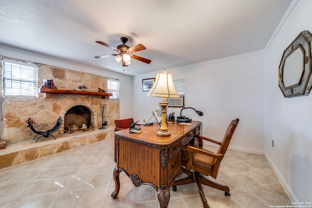 tiled office featuring ceiling fan, a stone fireplace, ornamental molding, and a textured ceiling