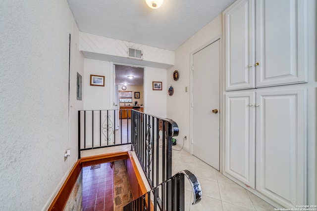 hallway featuring a textured ceiling and light tile patterned flooring