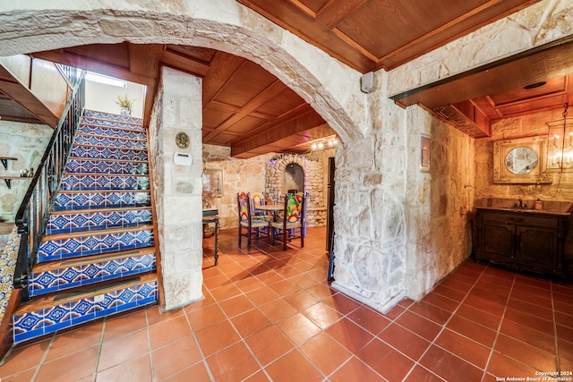 interior space featuring tile patterned floors, beam ceiling, wood ceiling, and a chandelier