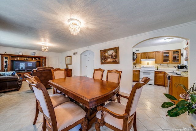 dining area with light tile patterned floors, ornamental molding, a textured ceiling, and a notable chandelier