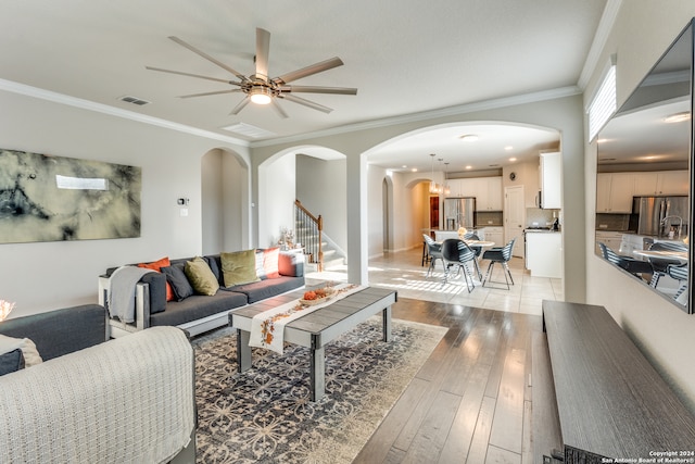 living room featuring ceiling fan, light hardwood / wood-style floors, and ornamental molding