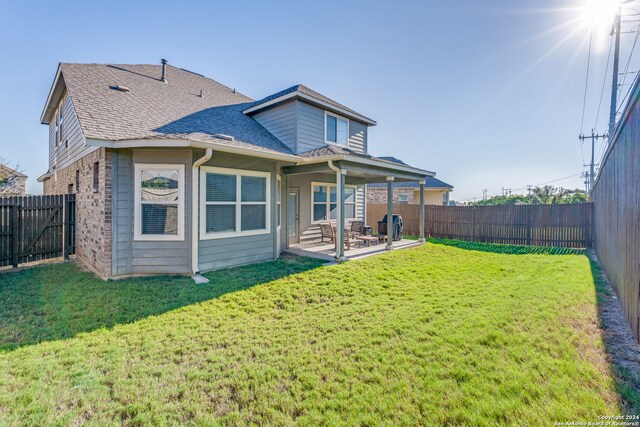 back of property with a yard and a patio