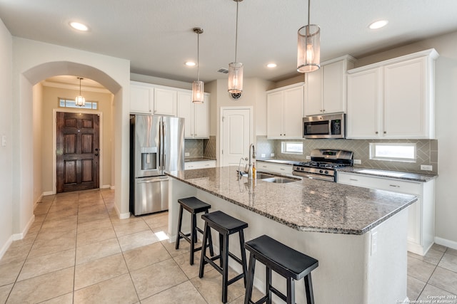 kitchen featuring white cabinets, appliances with stainless steel finishes, a center island with sink, and sink