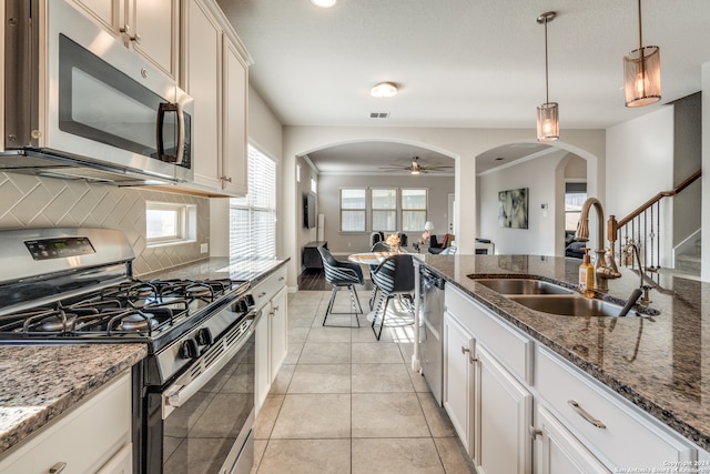 kitchen with plenty of natural light, stainless steel appliances, decorative light fixtures, and sink