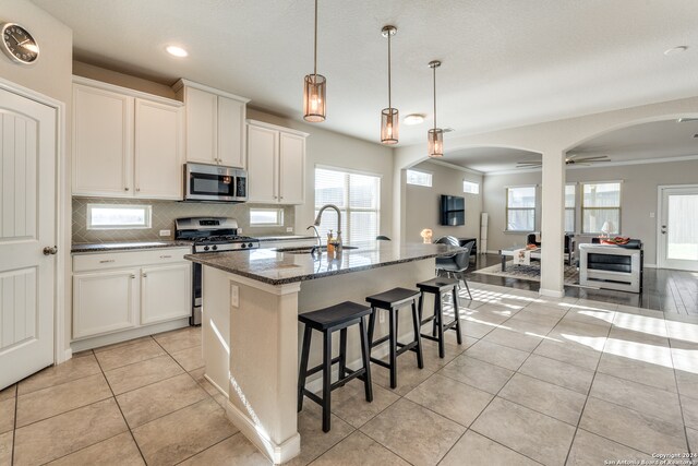 kitchen featuring white cabinets, sink, ceiling fan, an island with sink, and stainless steel appliances