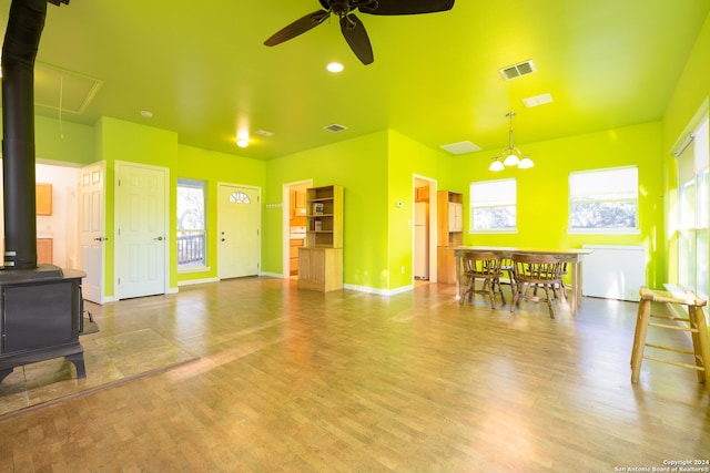 living room with a wood stove, ceiling fan, and light wood-type flooring