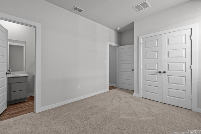 unfurnished bedroom with light carpet, connected bathroom, and a closet