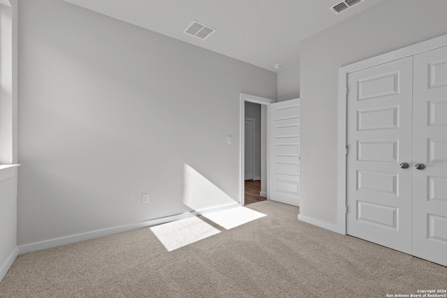 unfurnished bedroom featuring light colored carpet and a closet