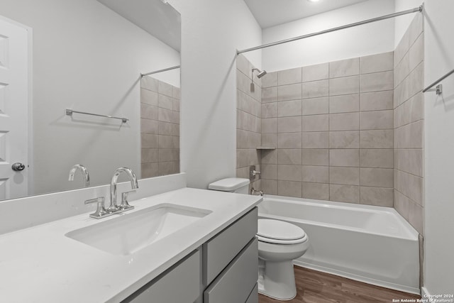 full bathroom with hardwood / wood-style floors, tiled shower / bath combo, toilet, and vanity