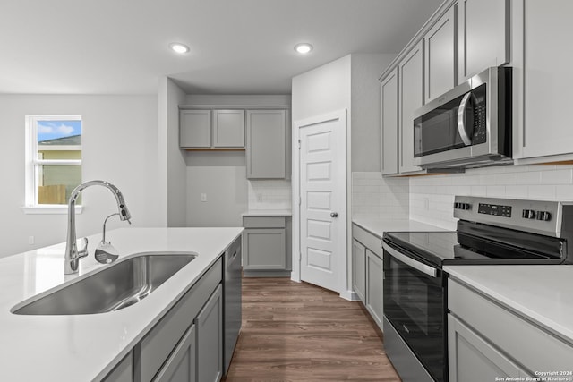 kitchen with gray cabinetry, sink, dark hardwood / wood-style flooring, backsplash, and appliances with stainless steel finishes