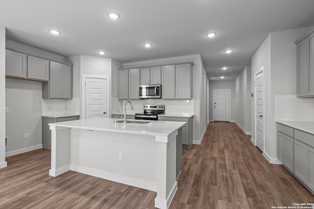 kitchen featuring gray cabinetry, sink, dark wood-type flooring, an island with sink, and appliances with stainless steel finishes