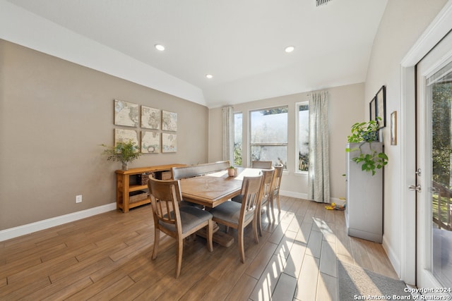 dining space with vaulted ceiling and light hardwood / wood-style flooring