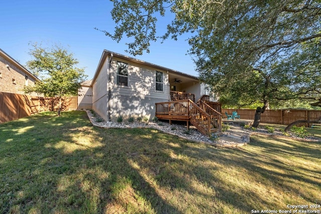 rear view of property featuring a yard, a deck, and ceiling fan