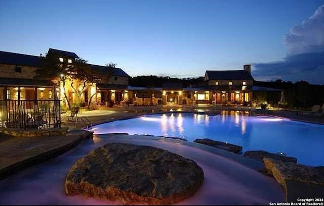 pool at dusk with a patio area