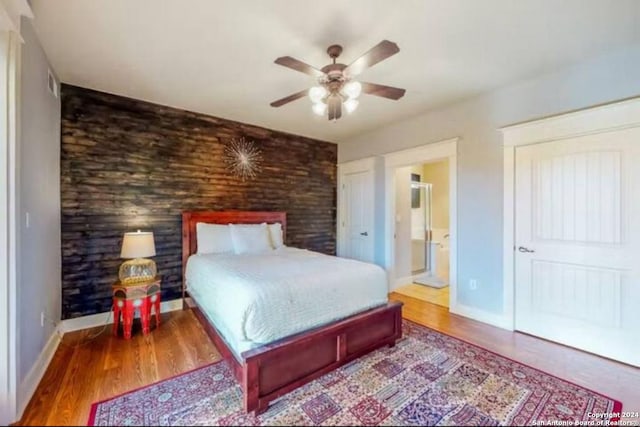 bedroom featuring ensuite bath, ceiling fan, and wood-type flooring