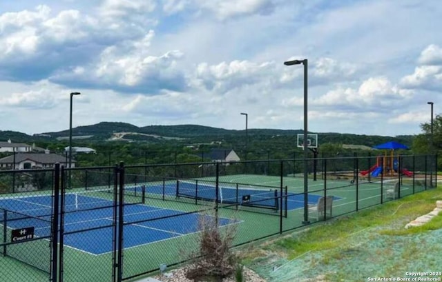 view of sport court featuring a mountain view and a playground