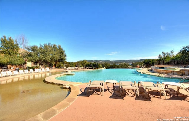 view of pool with pool water feature, a hot tub, and a patio area