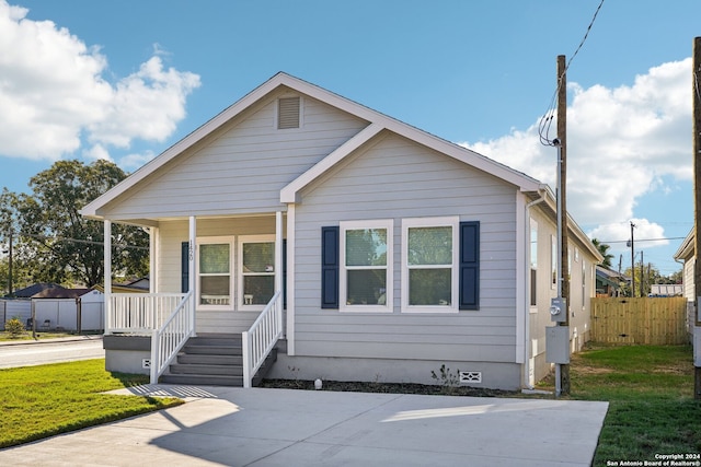 bungalow-style house featuring covered porch and a front lawn