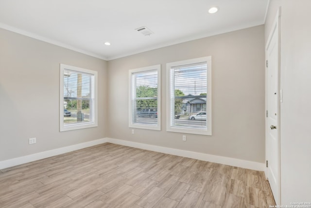 spare room with crown molding and light wood-type flooring