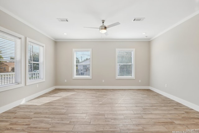 empty room featuring light wood-type flooring, ornamental molding, and a wealth of natural light