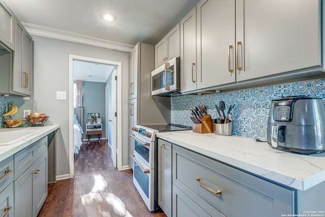 kitchen with tasteful backsplash, dark wood-type flooring, crown molding, range, and gray cabinets