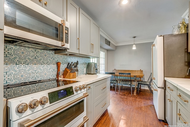 kitchen featuring white appliances, dark wood-type flooring, hanging light fixtures, ornamental molding, and light stone counters