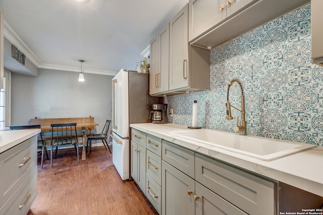 kitchen with sink, ornamental molding, pendant lighting, gray cabinets, and hardwood / wood-style flooring