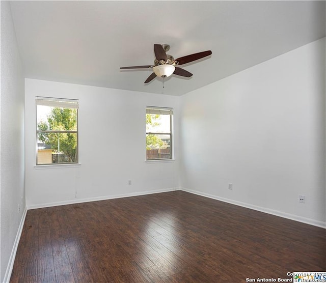 empty room with ceiling fan, dark wood-type flooring, and a healthy amount of sunlight