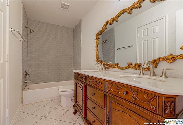 full bathroom with vanity, tiled shower / bath combo, and toilet