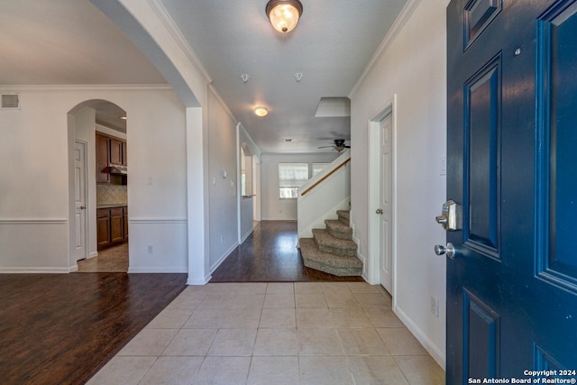 entryway with light wood-type flooring, ceiling fan, and ornamental molding