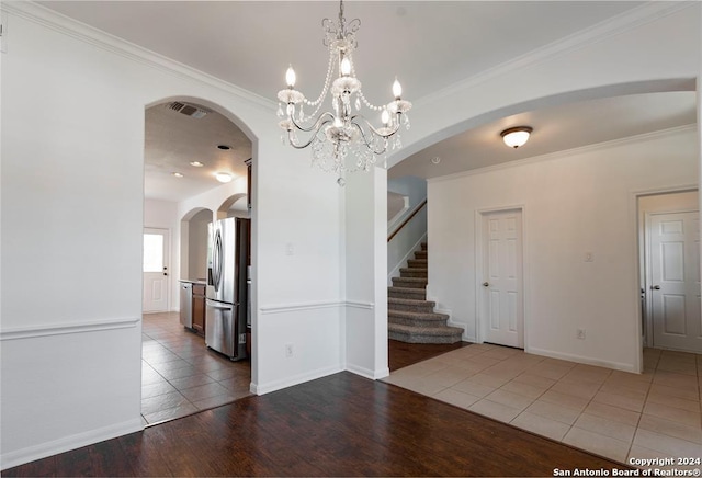 spare room featuring hardwood / wood-style flooring, an inviting chandelier, and ornamental molding