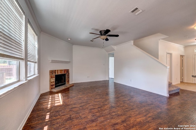 unfurnished living room featuring ceiling fan, dark hardwood / wood-style flooring, crown molding, and a brick fireplace