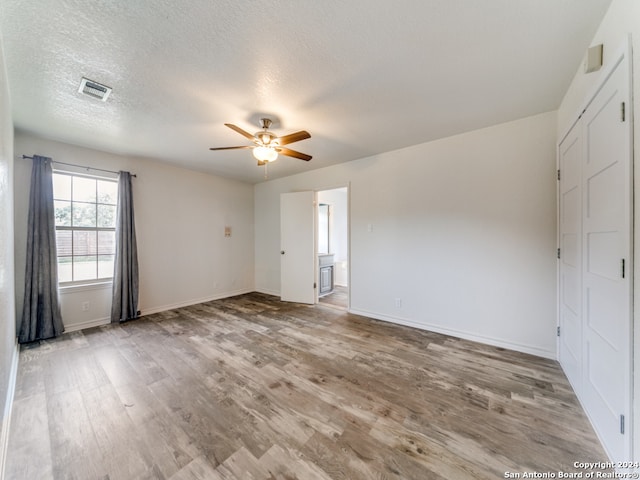 spare room with ceiling fan, light hardwood / wood-style floors, and a textured ceiling