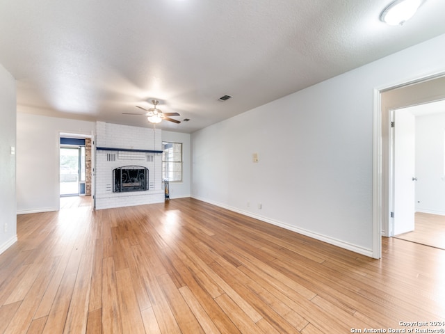 unfurnished living room featuring a fireplace, a textured ceiling, light hardwood / wood-style floors, and ceiling fan