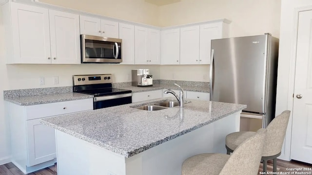 kitchen featuring white cabinetry, sink, stainless steel appliances, dark hardwood / wood-style flooring, and a kitchen island with sink