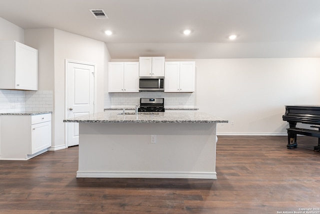 kitchen with appliances with stainless steel finishes, dark hardwood / wood-style floors, white cabinetry, and a kitchen island with sink