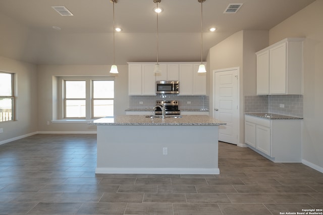 kitchen featuring light stone countertops, white cabinetry, hanging light fixtures, and appliances with stainless steel finishes