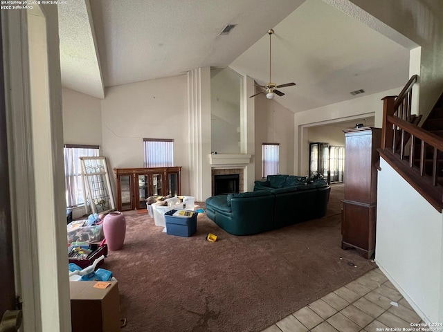 carpeted living room featuring a fireplace, a textured ceiling, high vaulted ceiling, and ceiling fan