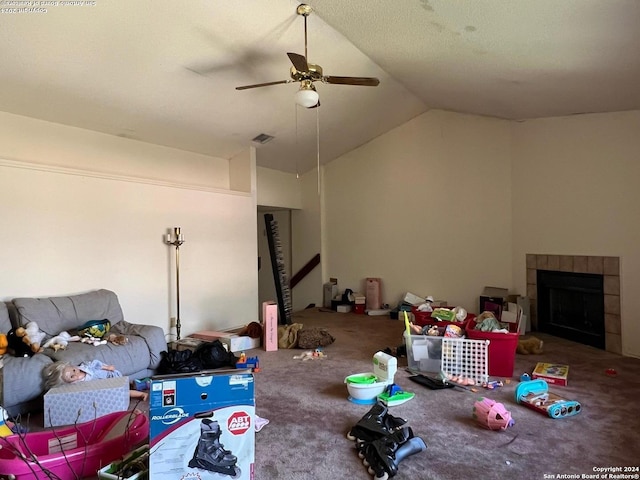 carpeted living room featuring ceiling fan, lofted ceiling, and a tiled fireplace