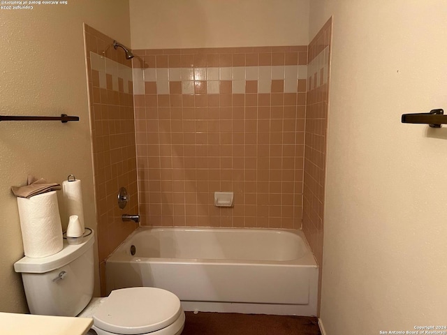 bathroom with tiled shower / bath combo and toilet