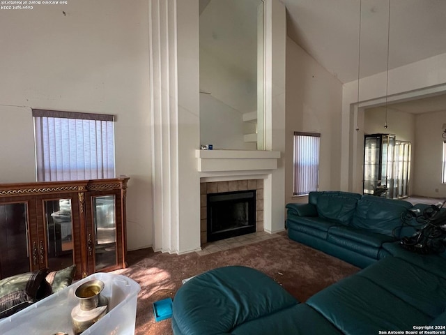 carpeted living room with a tile fireplace and high vaulted ceiling