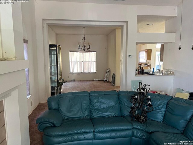 carpeted living room with an inviting chandelier