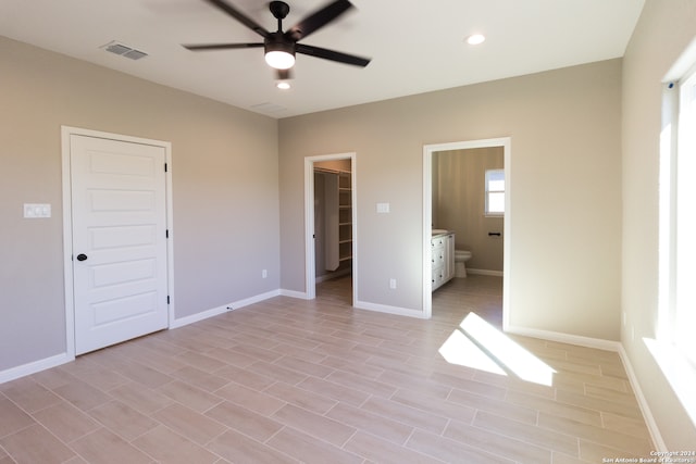 unfurnished bedroom featuring ceiling fan, light hardwood / wood-style floors, connected bathroom, and a closet