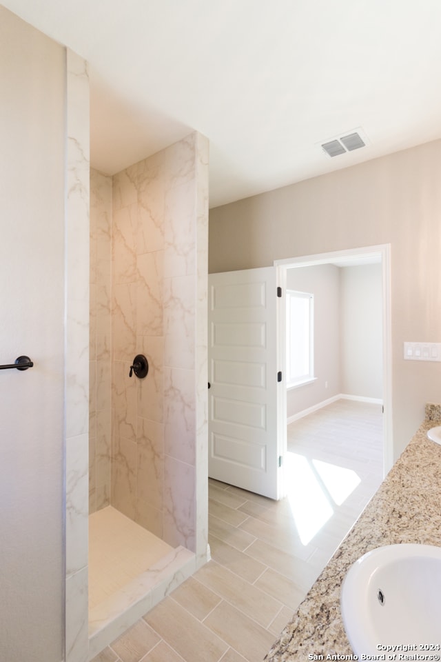 bathroom with vanity and a tile shower