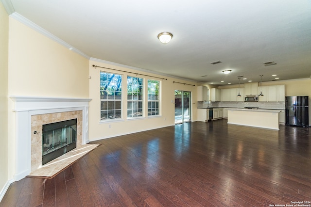 unfurnished living room featuring dark hardwood / wood-style flooring, ornamental molding, and a tiled fireplace