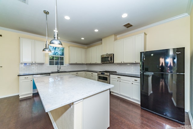 kitchen featuring appliances with stainless steel finishes, dark wood-type flooring, sink, a center island, and hanging light fixtures